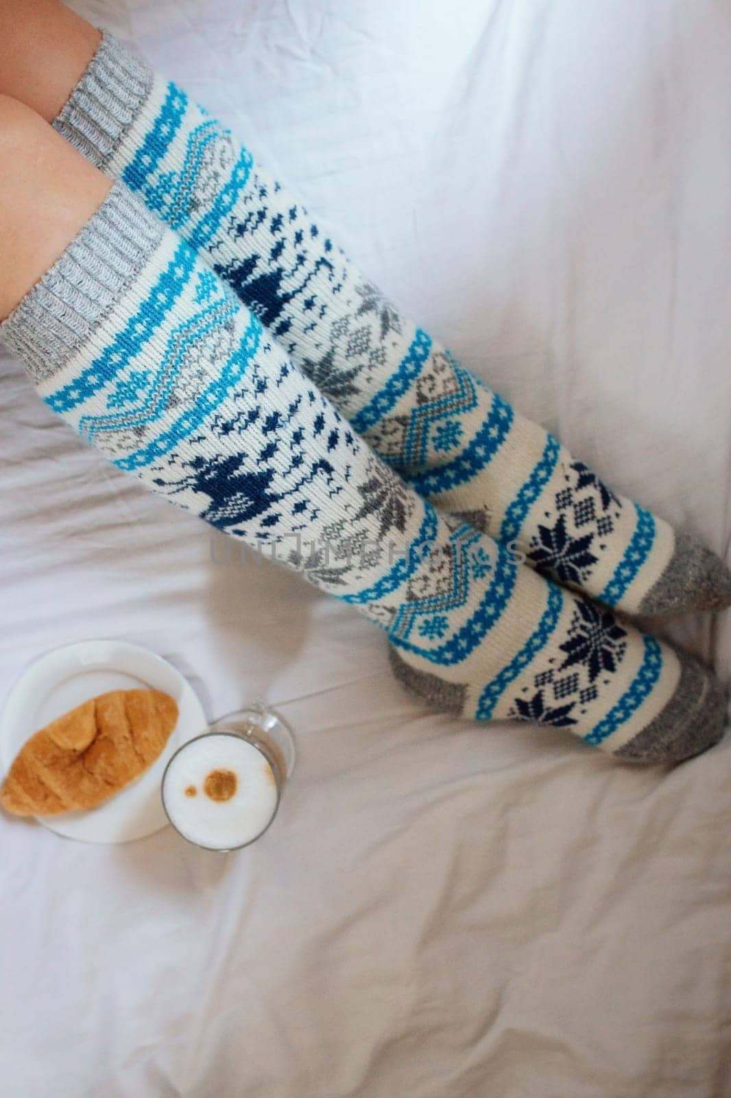 A young beautiful woman in warm handmade knitted clothes at home. . spring, winter season. Gaiters. Knee socks. Leggings.