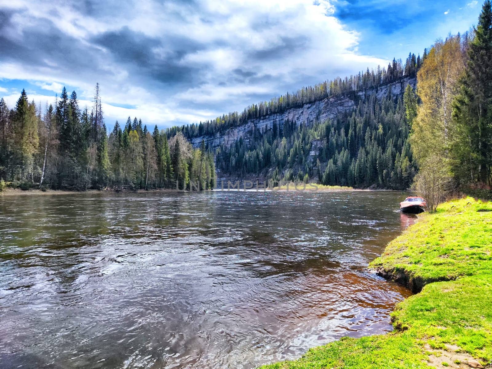 A tranquil river winds through vibrant trees under a dramatic sky.