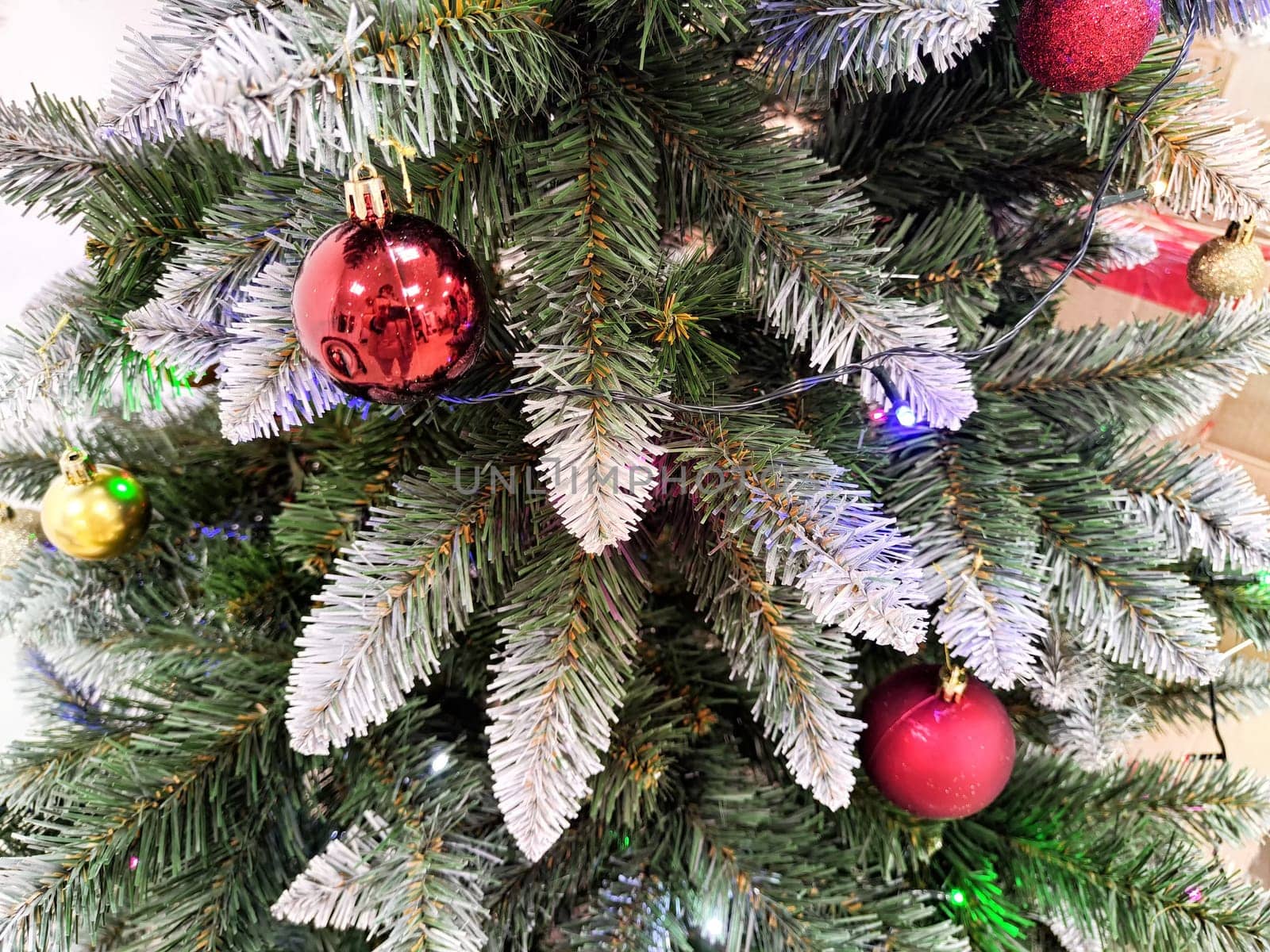 A Christmas tree adorned with bright red and gold ornaments stands in a warm indoor environment, capturing the festive spirit of the holidays.
