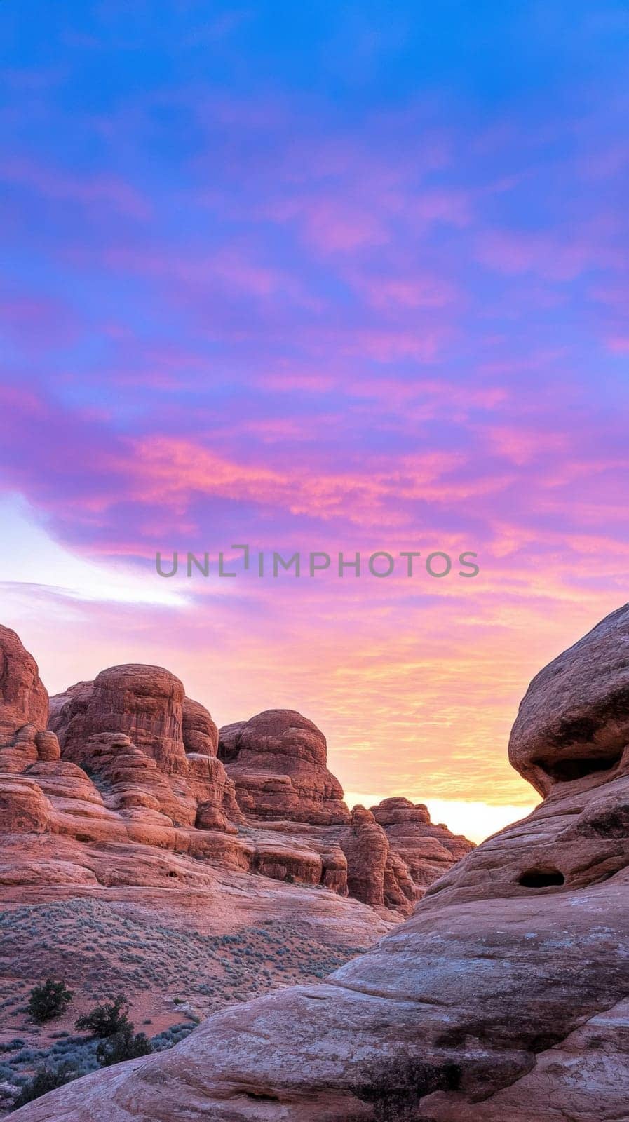 A breathtaking view of rock formations bathed in the warm hues of a sunset. The sky transitions from deep blue to pink and orange, highlighting the rugged beauty of the terrain. Perfect for nature and travel themes