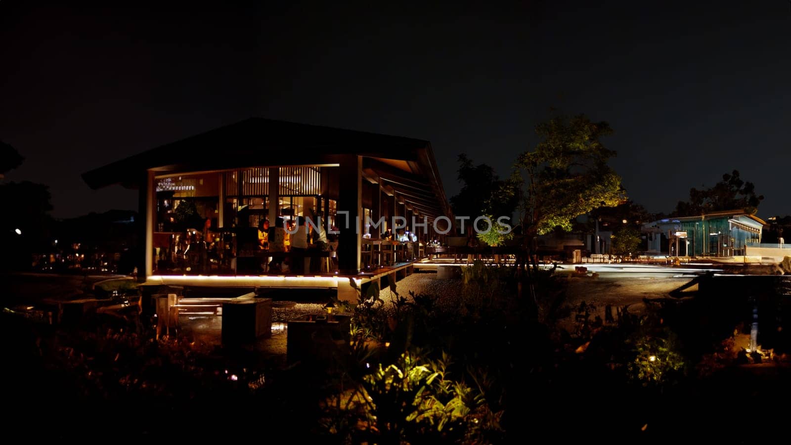 Nighttime view of a modern house with illuminated interiors and surrounding landscape.