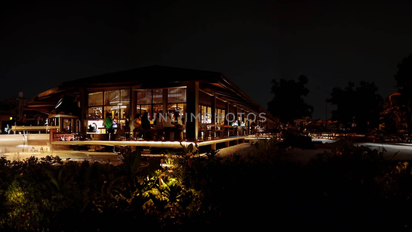 Modern restaurant with illuminated facade at night, surrounded by darkness, offering a cozy dining atmosphere.