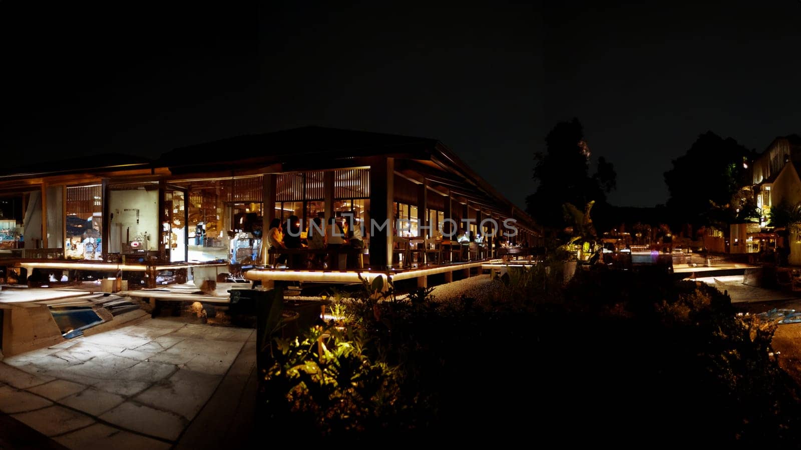 Nighttime view of a modern house with illuminated interiors and exterior lighting, showcasing elegant architecture and landscaping.