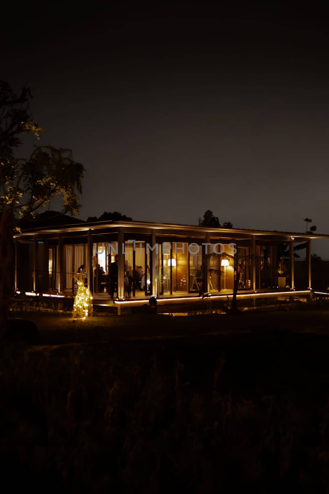 Cozy illuminated house at night with warm glowing lights and a tranquil dark sky background.
