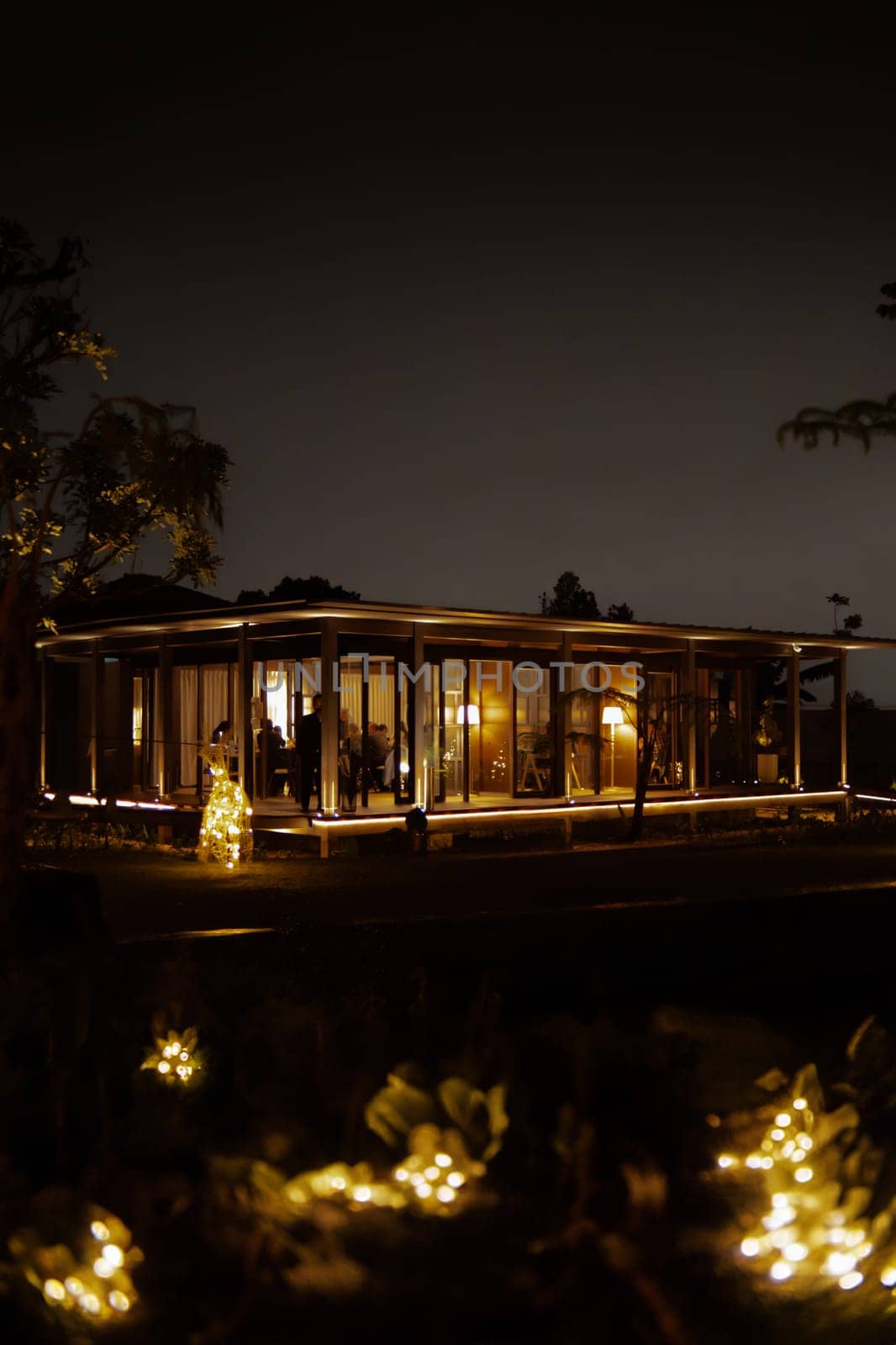 Cozy house lit up at night with warm lights, surrounded by darkness.