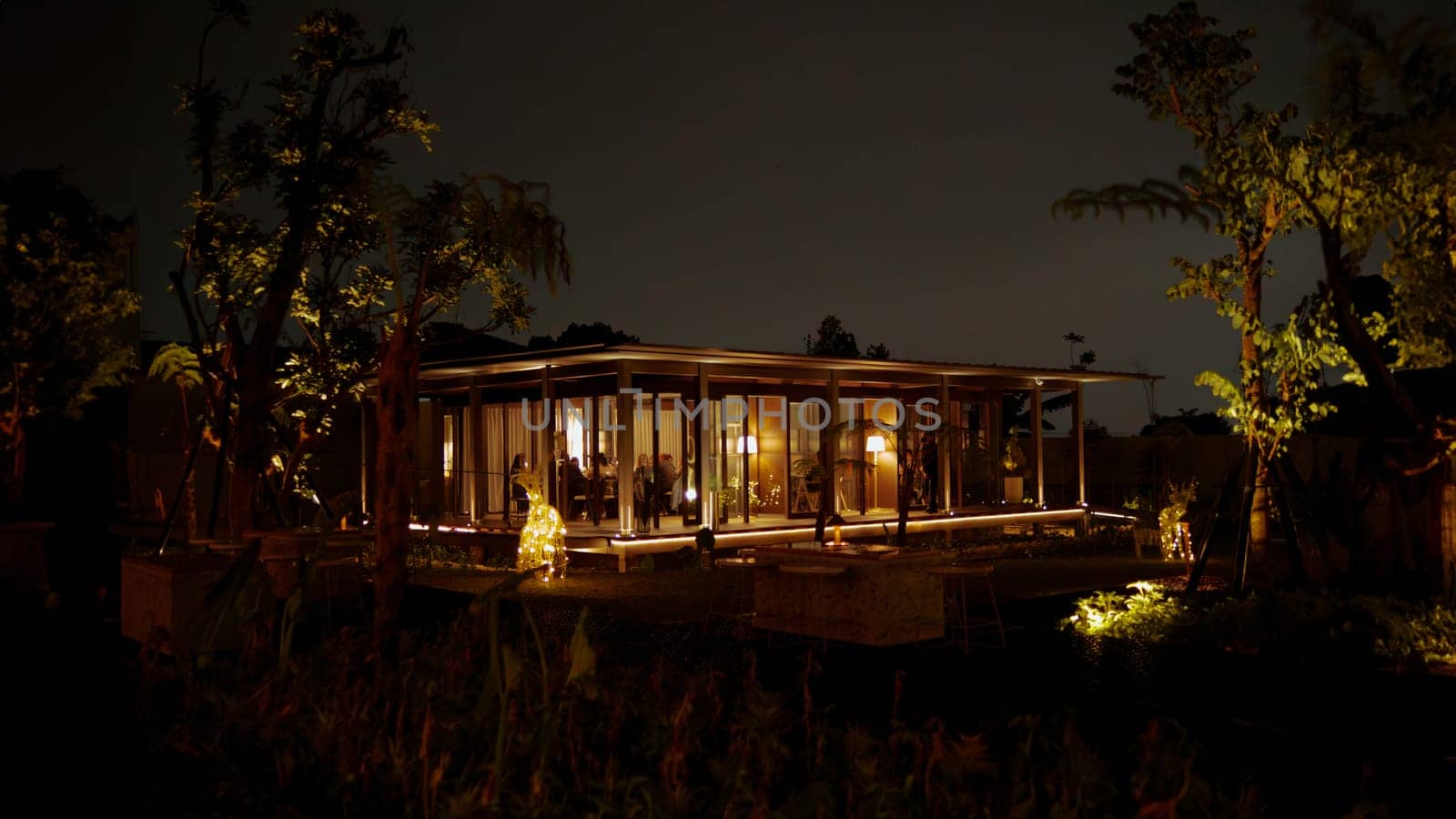 Cozy illuminated cabin at night surrounded by trees, offering a tranquil and inviting atmosphere in the dark night
