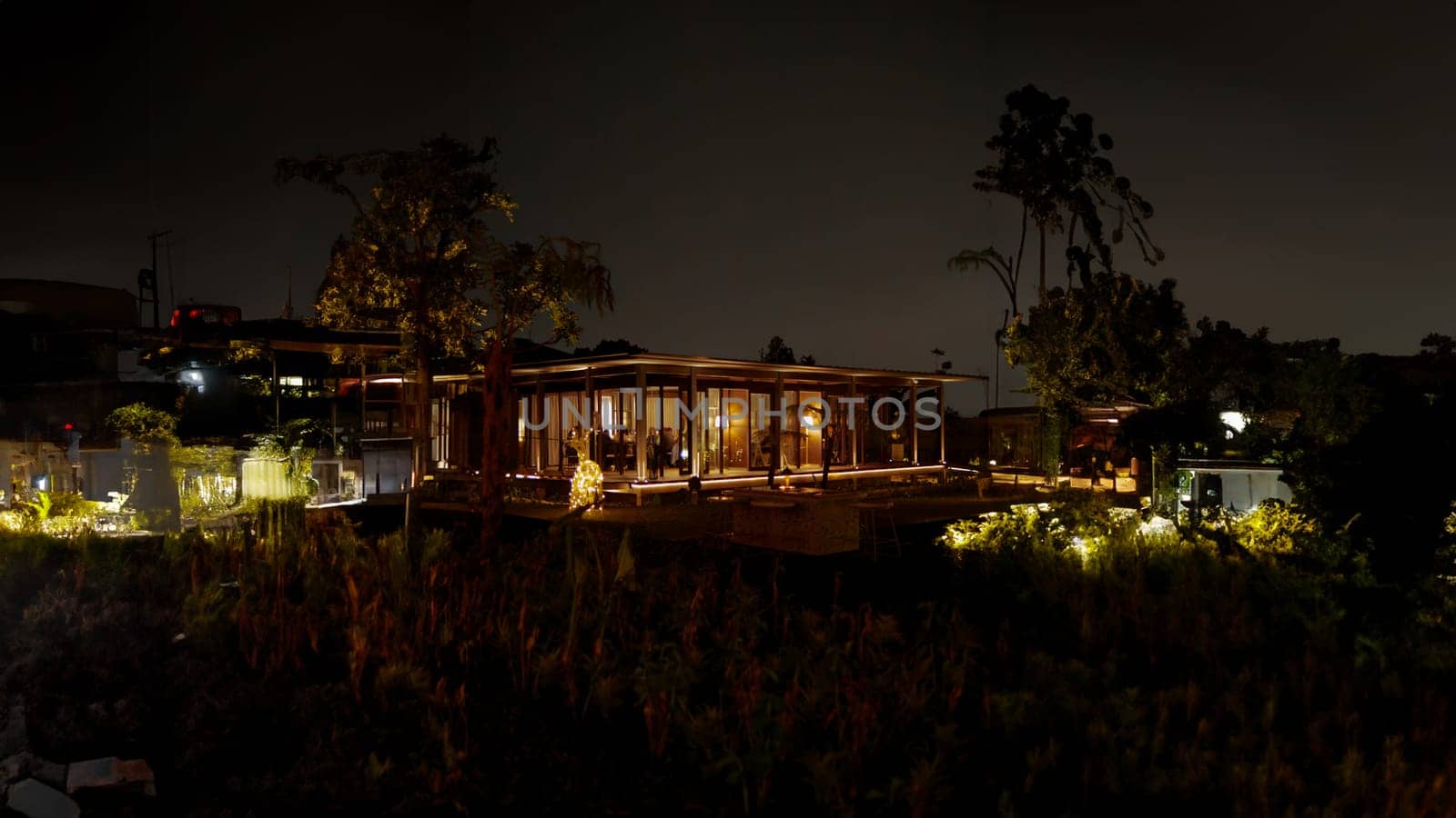 Serene night landscape with illuminated house amidst dark surroundings, highlighting tranquil suburban life in the dark night