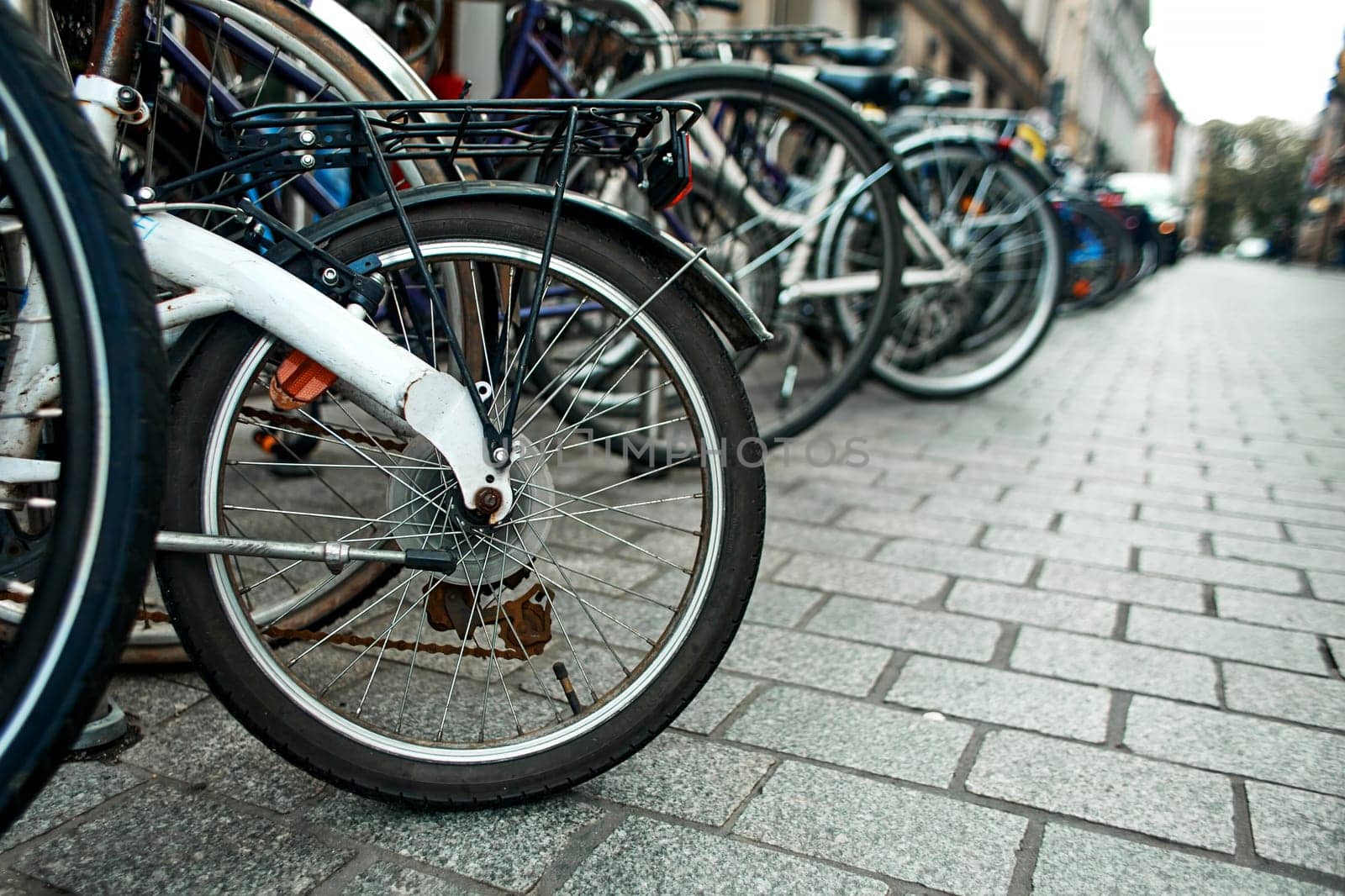Close-up of a wheel in a row of parked bicycles on the streets of Europe