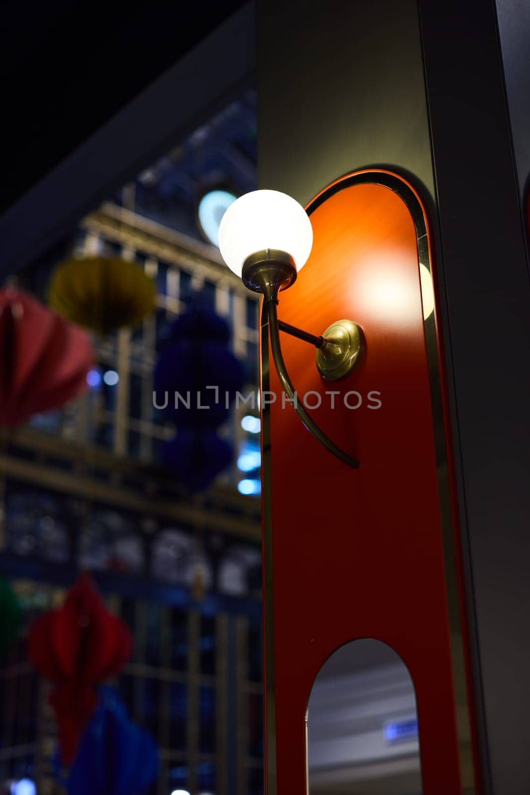 A beautifully designed and stylish wall sconce that illuminates a vibrant interior space full of colorful elements