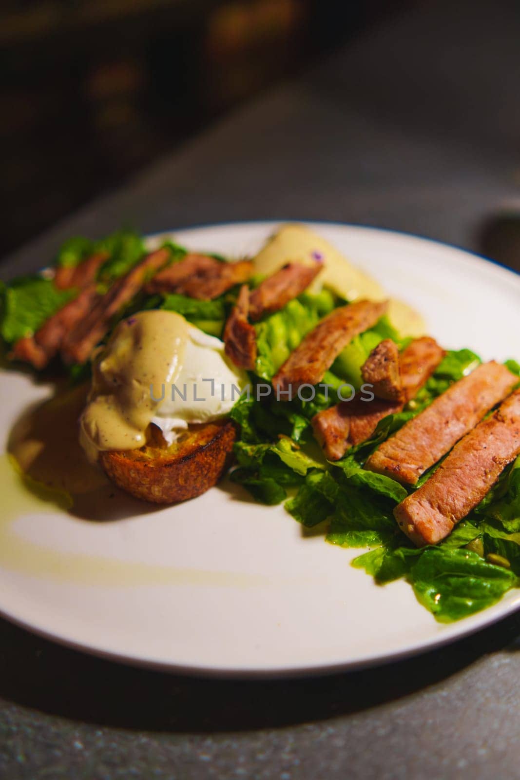 Gourmet Caesar salad with grilled chicken and dressing on a white plate in a cafe and roaster