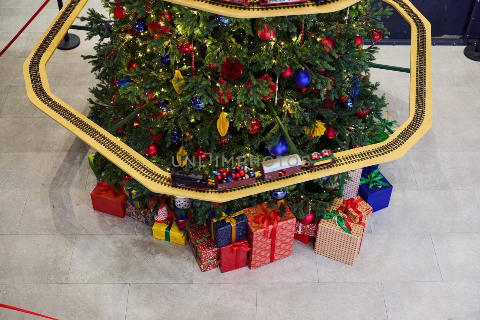 A beautifully decorated Christmas tree that is elegantly adorned with colorful gifts and a charming toy train