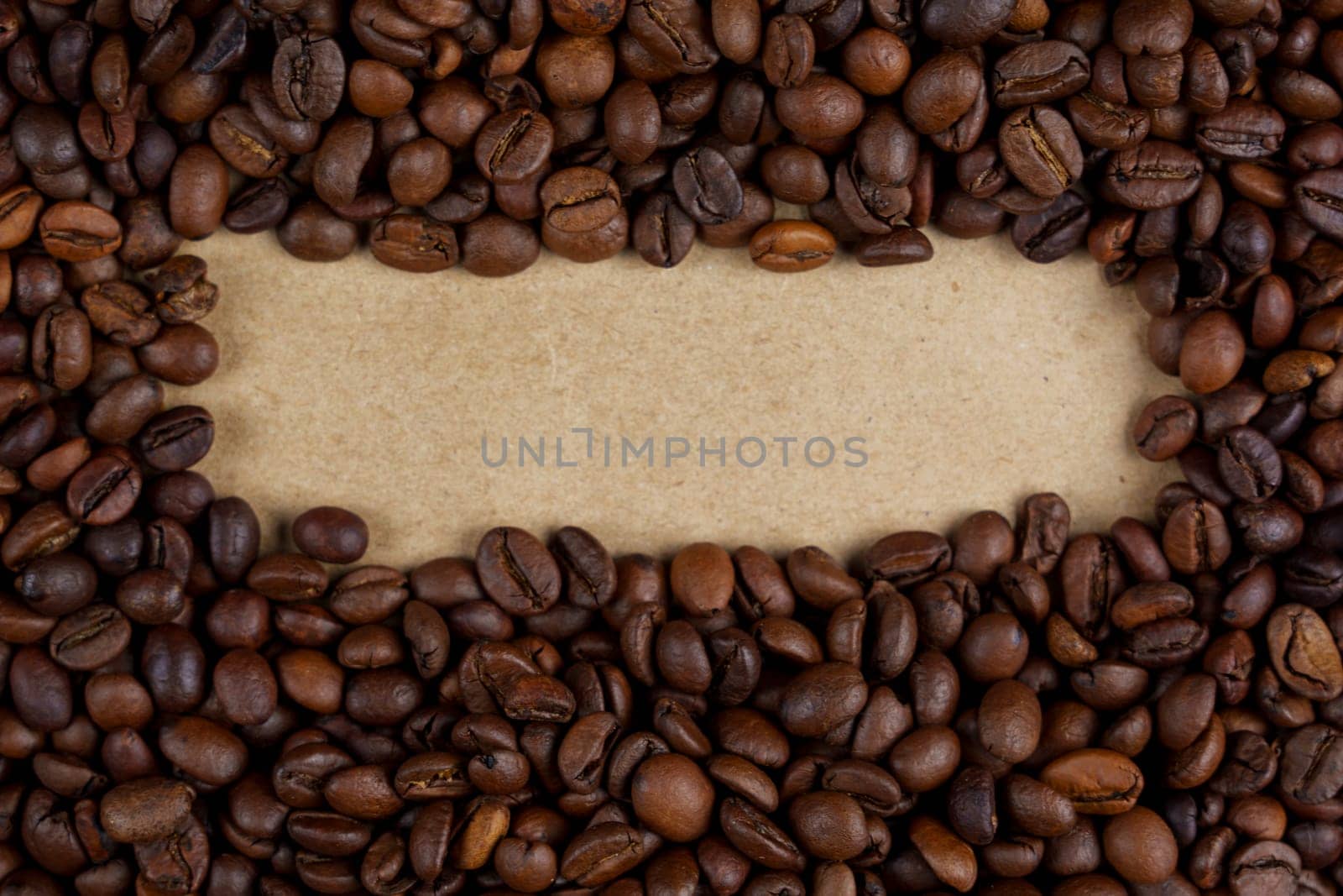 Roasted coffee beans creating a natural frame around a blank kraft paper area, ideal for adding text or design elements, rustic and organic, no people.