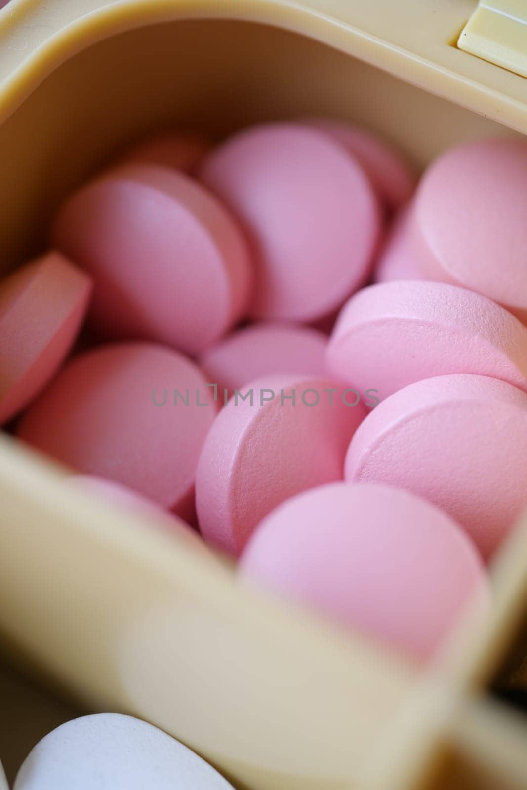 A closeup photo shows neatly arranged pink pills in a container, highlighting their color