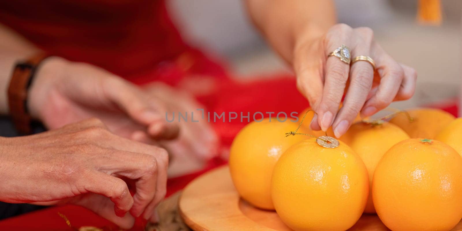 An elderly Chinese couple joyfully prepares for Chinese New Year showcasing traditional fruits in a festive home setting.