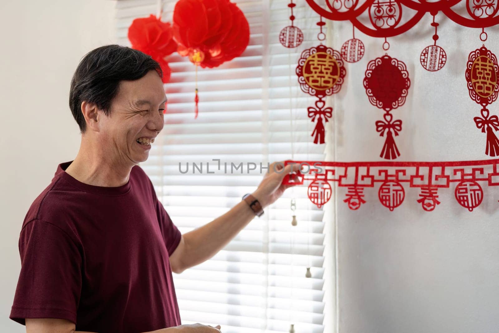 An elderly Chinese couple joyfully prepares their home for the New Year embracing cultural traditions and festive decorations.