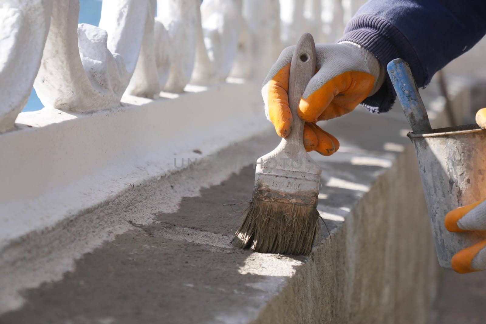 A dedicated worker skillfully painting the surface of a concrete structure with a brush outdoors