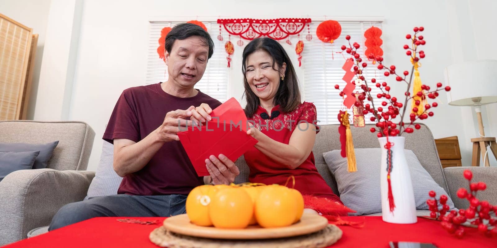A joyful elderly Chinese couple celebrates Chinese New Year at home sharing love and traditions in a festive atmosphere.