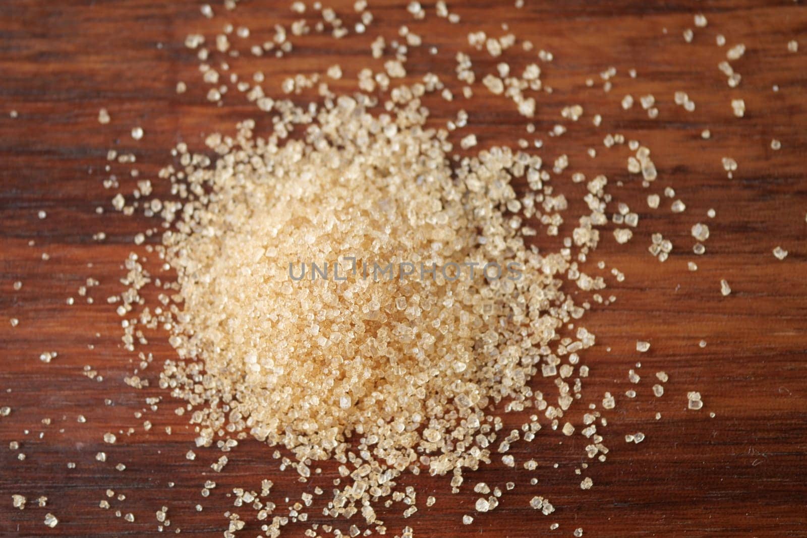 Here is a detailed closeup view of brown sugar granules spread out on a rustic wooden background