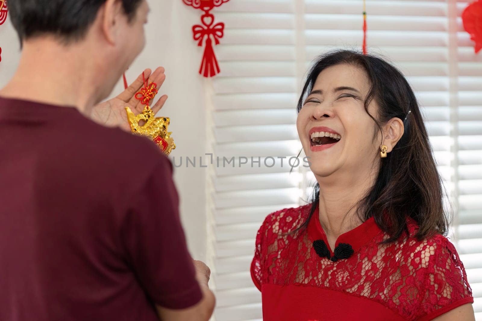 An elderly couple joyfully celebrates Chinese New Year embodying love and tradition in a festive home atmosphere.