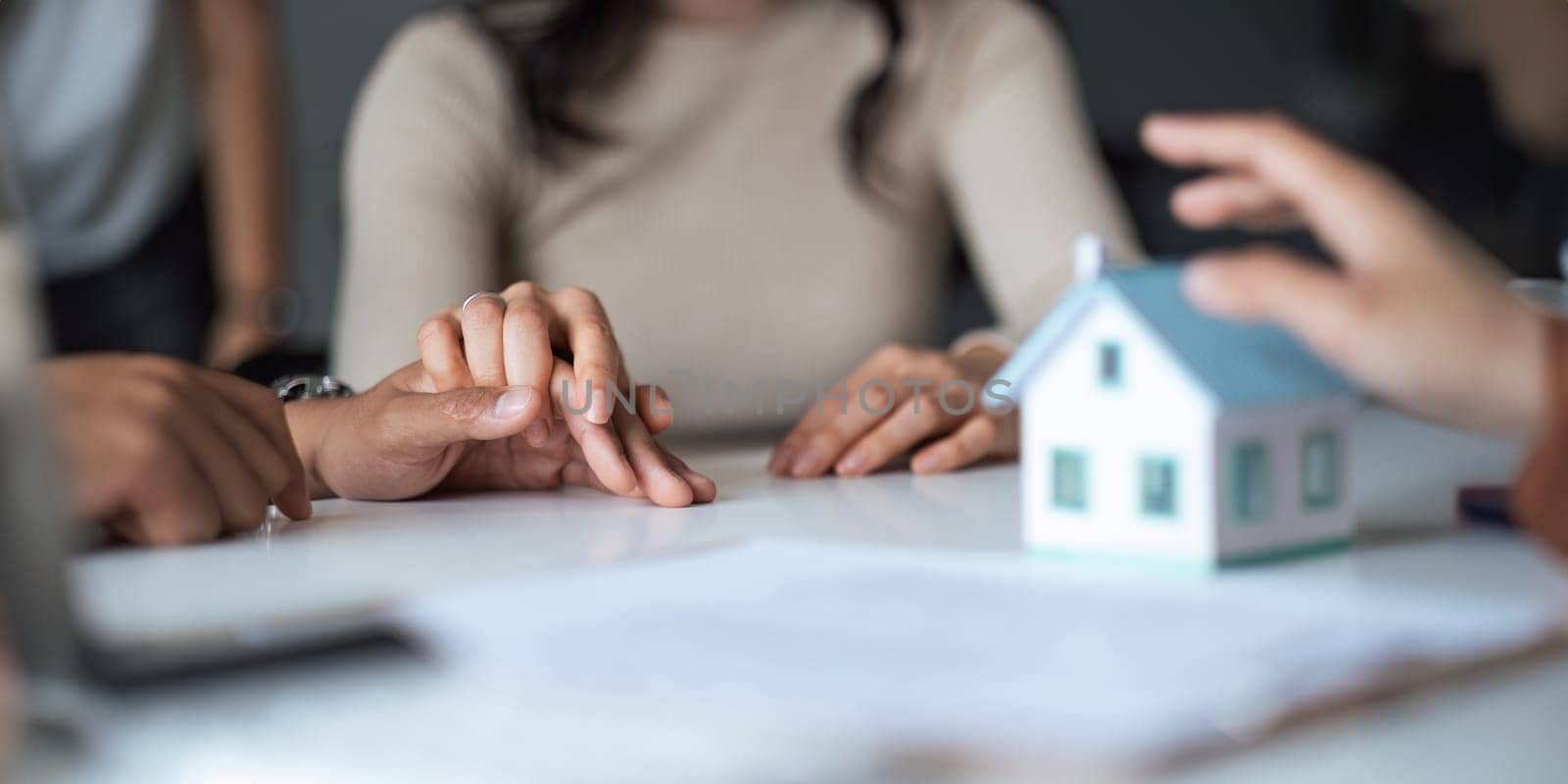 Young Asian couple making contract with house sale agency. man and his wife sitting signing the contract next to him looking the contract document with smile. real estate agreement successful concept.