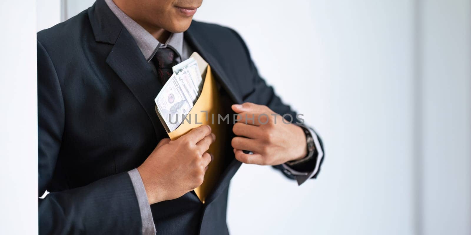 Businessman briefcase document envelope with dollar banknotes on white background. businessman putting illegal secret agreement money in his jacket. corruption, bribery, crime and embezzle concept by nateemee