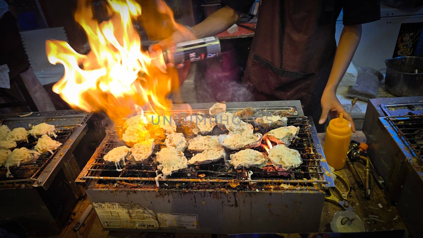 street vendor uses a torch flame to prepare delicious grilled oyster with flair and skill, showcasing the vibrant atmosphere of bustling night Thai markets. Good for recipe book