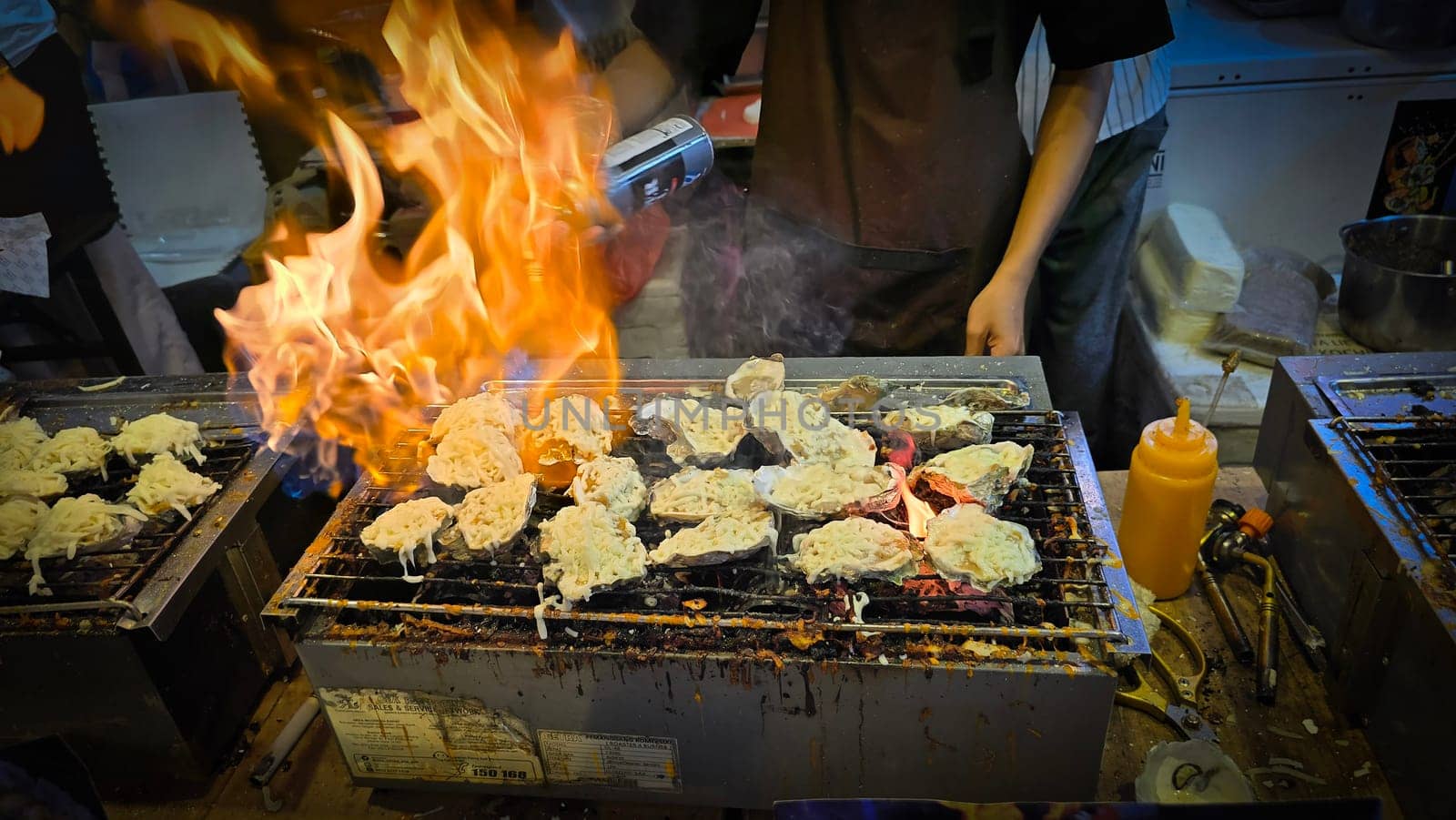 street vendor uses a torch flame to prepare delicious grilled oyster with flair and skill, showcasing the vibrant atmosphere of bustling night Thai markets. Good for recipe book