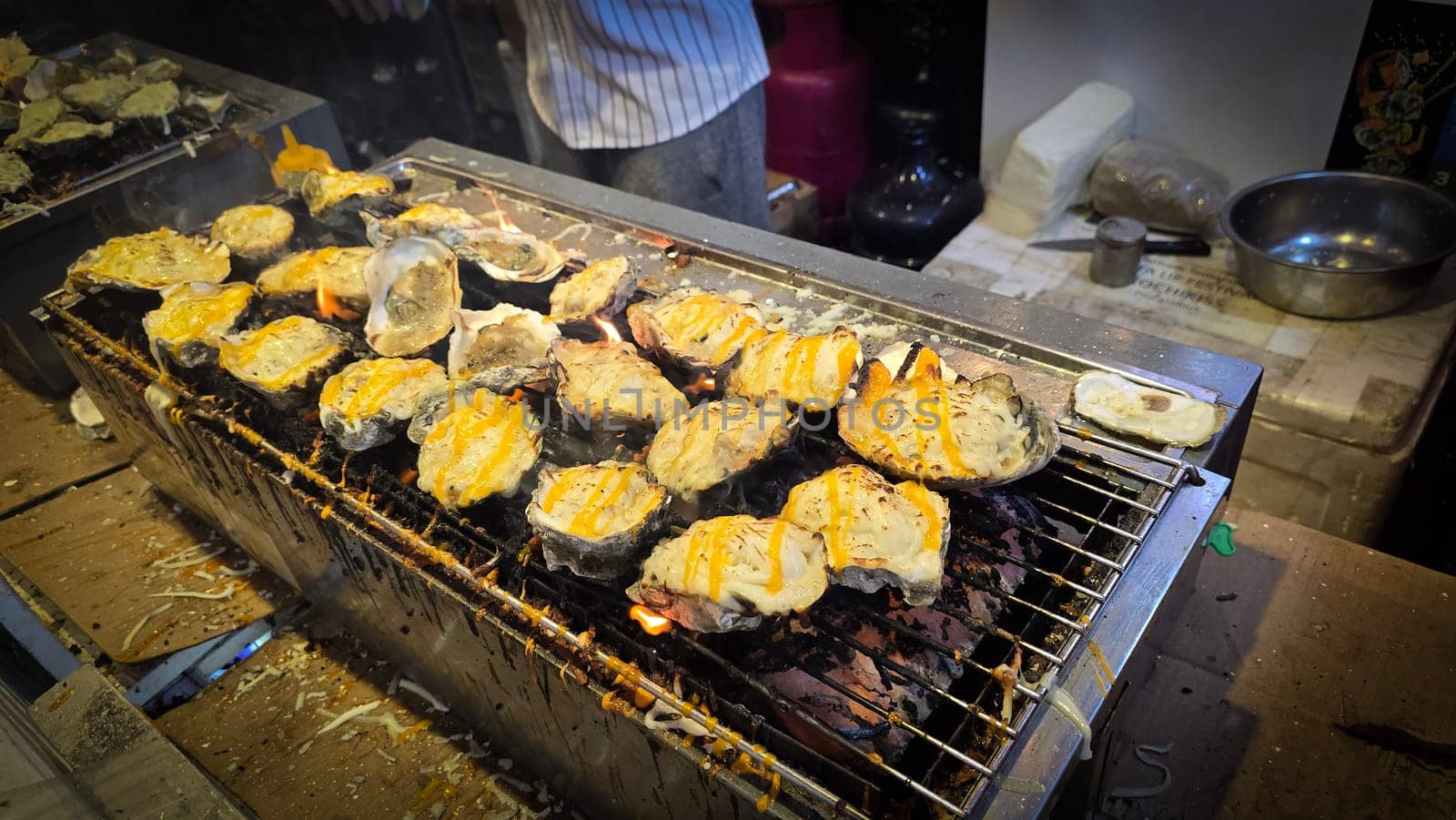 street vendor uses a torch flame to prepare delicious grilled oyster with flair and skill, showcasing the vibrant atmosphere of bustling night Thai markets. Good for recipe book