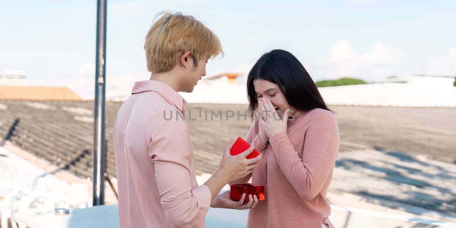 A heartfelt proposal scene captures a couple's love on a stunning rooftop filled with joy and surprise.