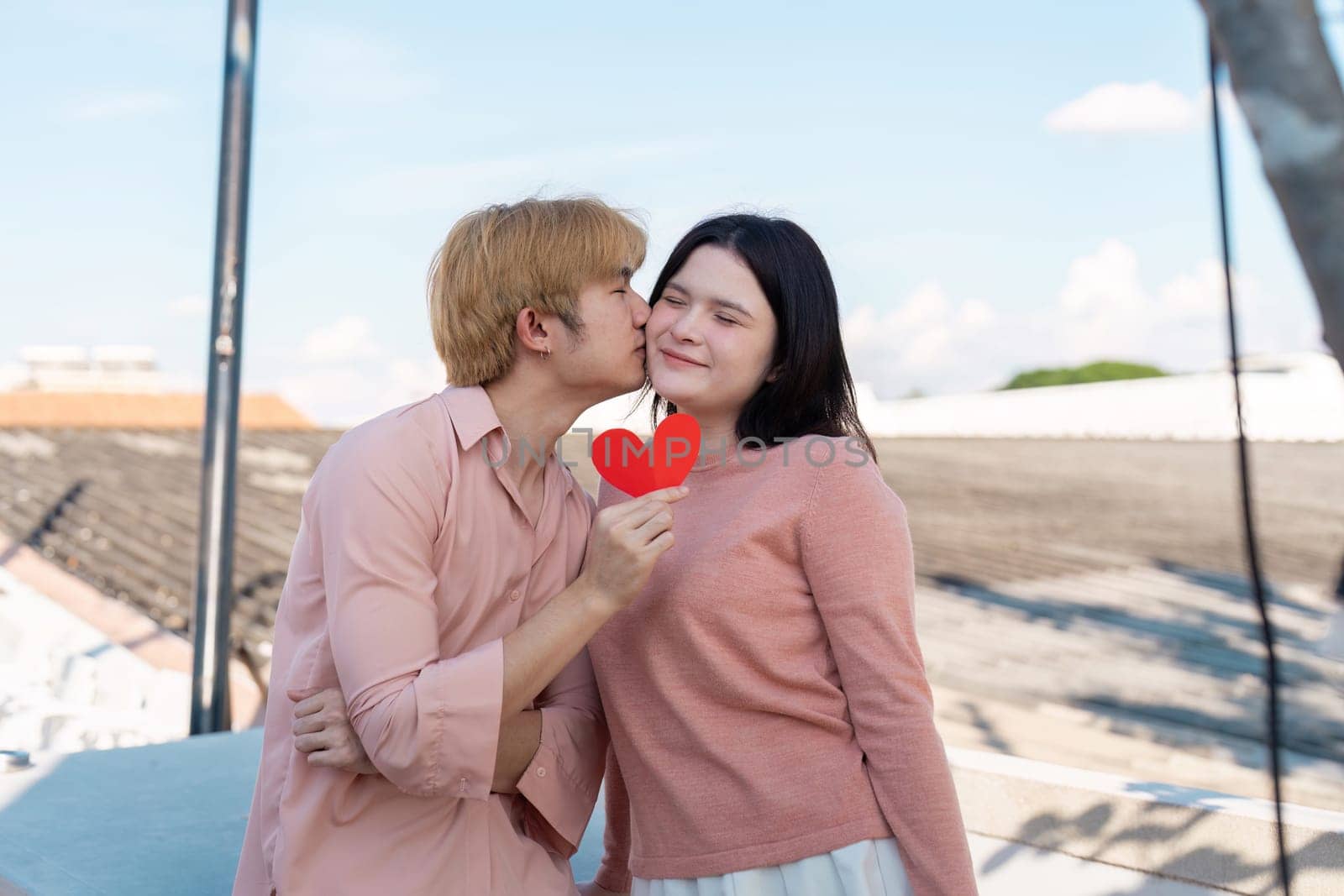 A couple shares a tender kiss on a rooftop while celebrating their love with a heart symbol embodying Valentine spirit.