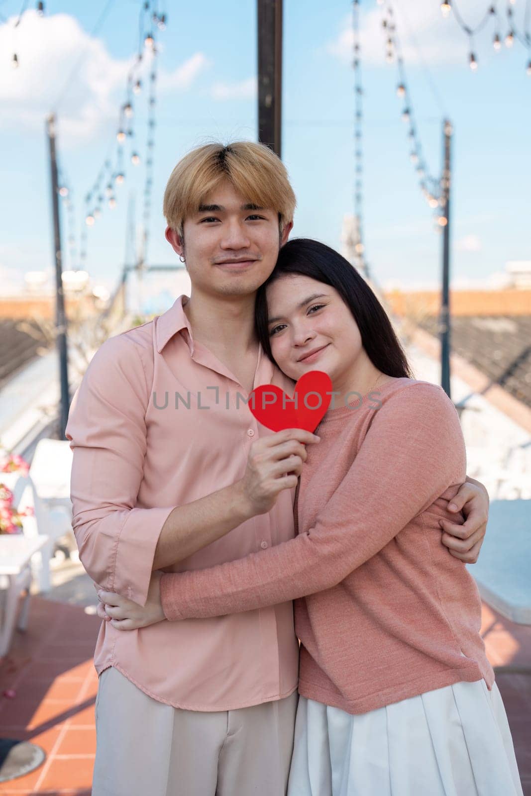 A couple joyfully celebrates Valentine Day on a rooftop capturing a heartfelt moment with a red heart symbol.