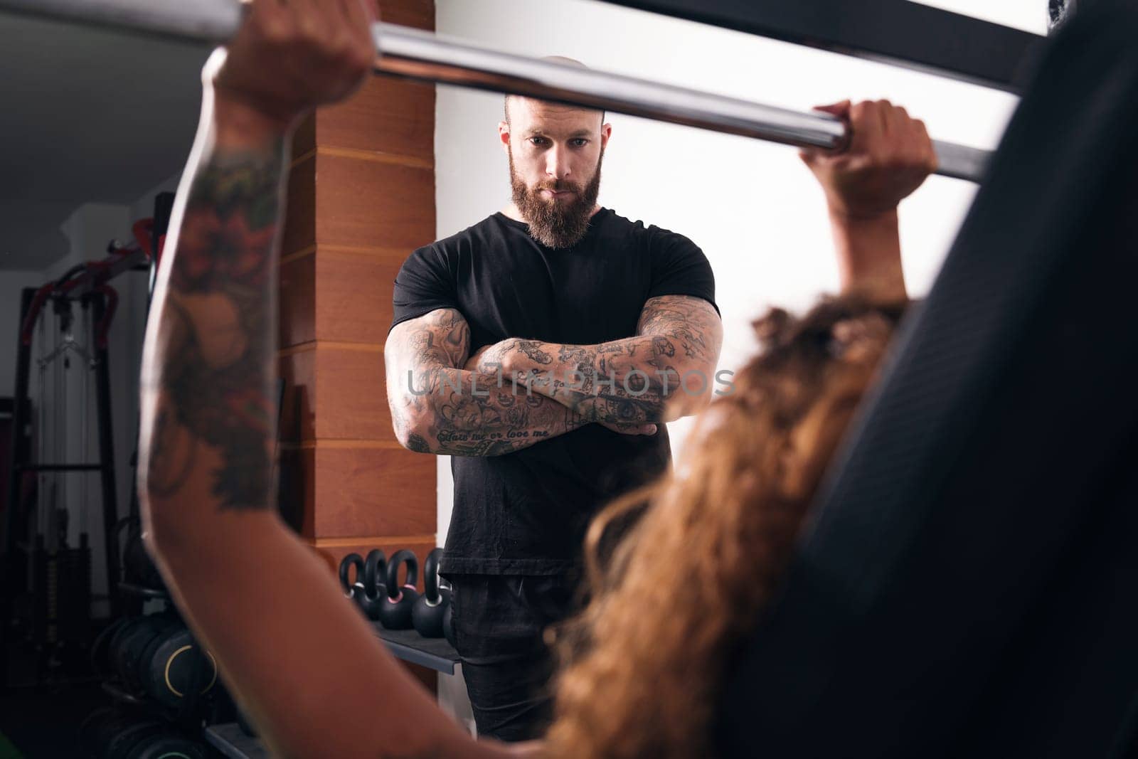 unrecognizable strong sportswoman lifting heavy barbell with weights during functional workout with instructor in gym, concept of fitness and active lifestyle