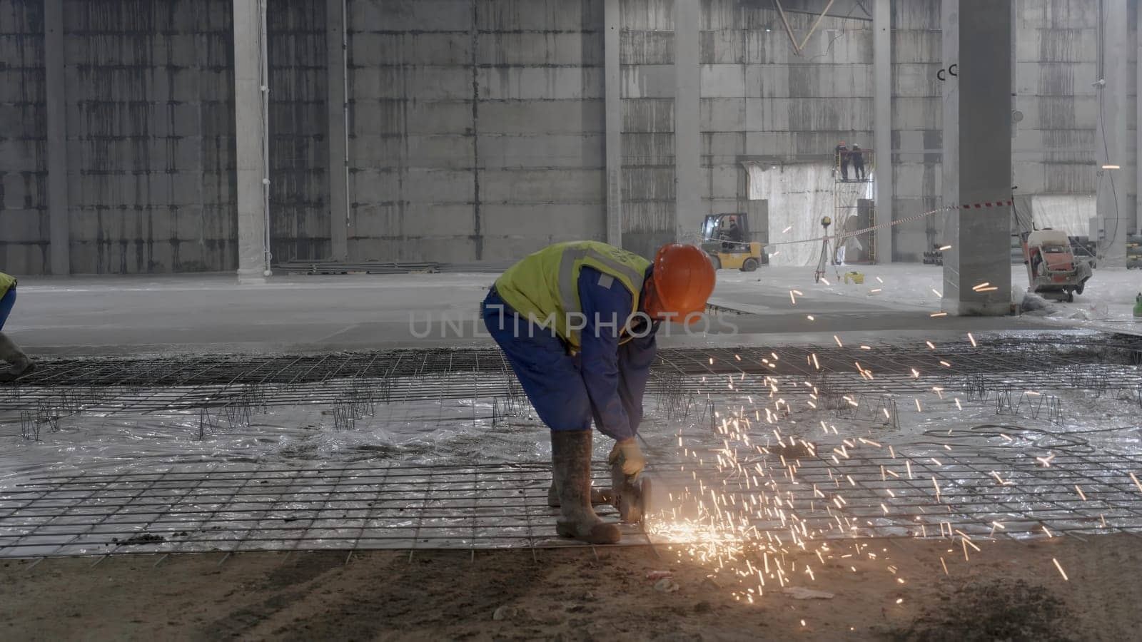 A worker diligently cutting metal in an industrial setting, creating bright sparks, showcasing active construction. Clip