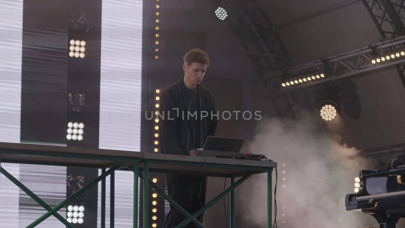 An artist showcases live electronic music performances on stage while providing captivating and engaging visuals. Clip