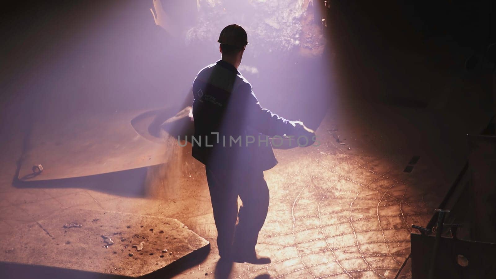 A man in a hard hat faces industrial challenges, walking through flames that symbolize overcoming obstacles, culminating in a well dressed man on stage, showcasing leadership and resilience. Stock Clip