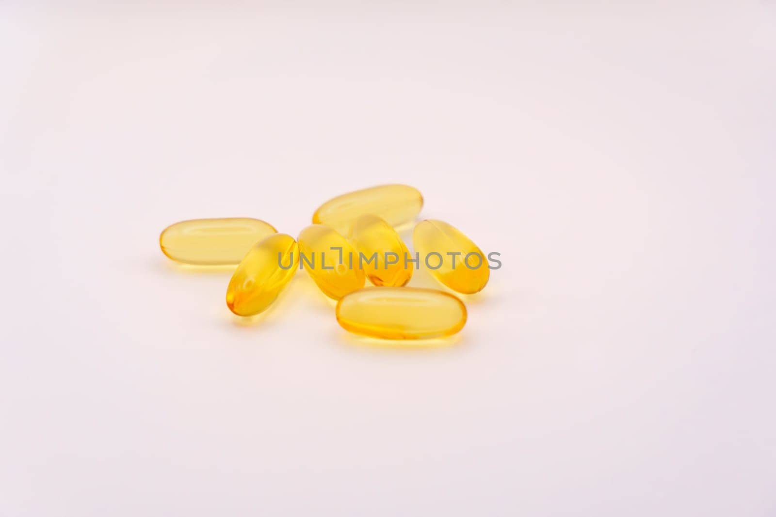 Group of yellow Omega-3 softgel capsules arranged on a clean white background, showcasing their translucent texture and vibrant color.