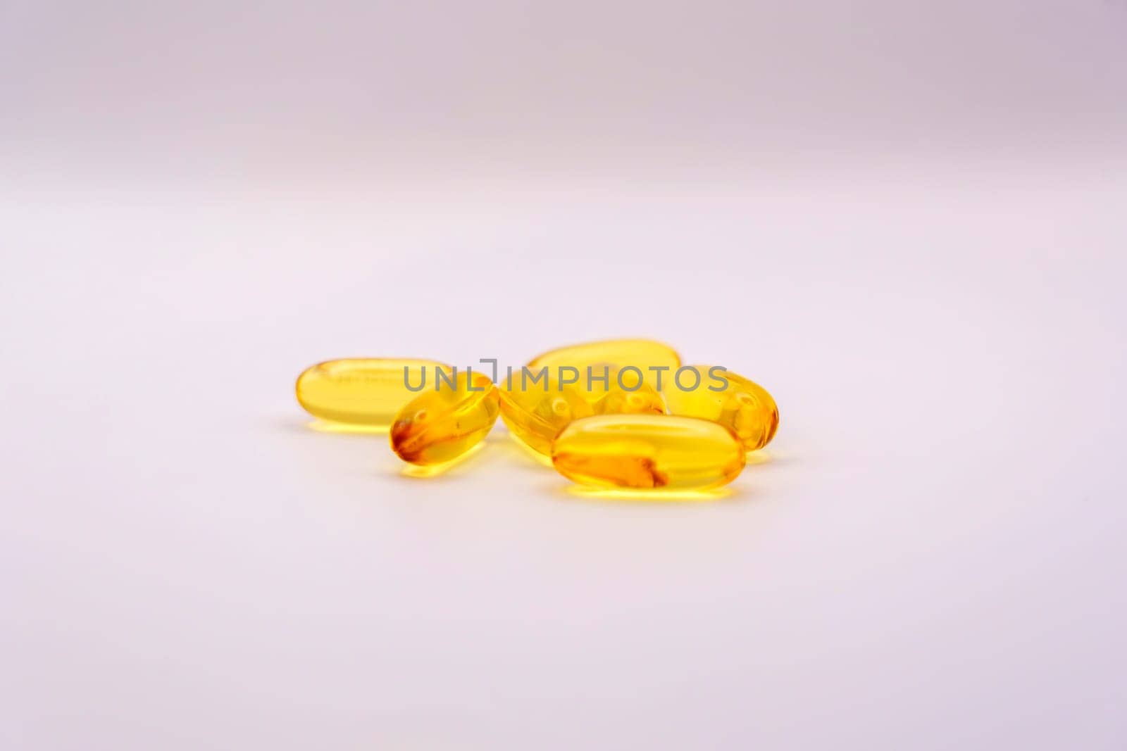 Close-up of Omega-3 softgel capsules with a glossy yellow finish, placed on a clean white background, emphasizing health and nutrition.
