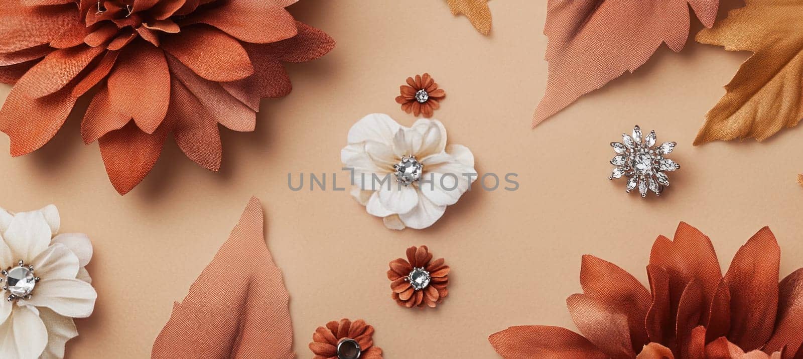 Stylish flat lay composition featuring orange and white flowers adorned with rhinestones, arranged on a beige background, creating a trendy and visually appealing floral pattern
