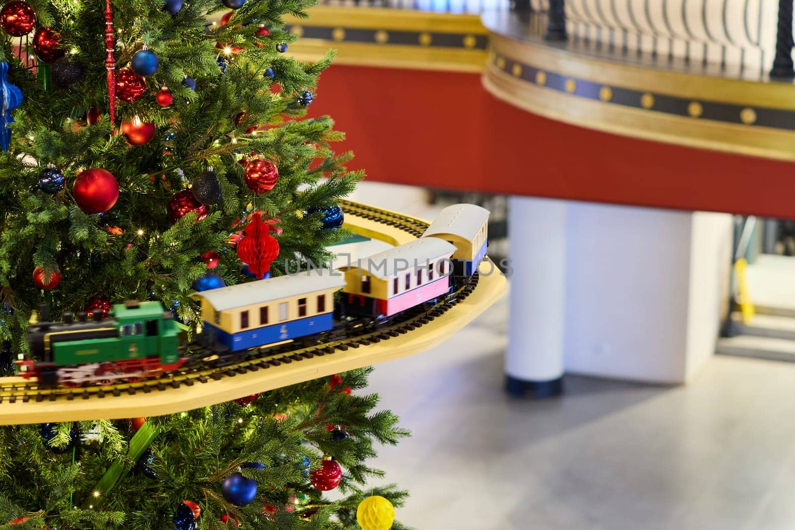 A beautifully vibrant Christmas tree brilliantly adorned with colorful decorations and a delightful toy train