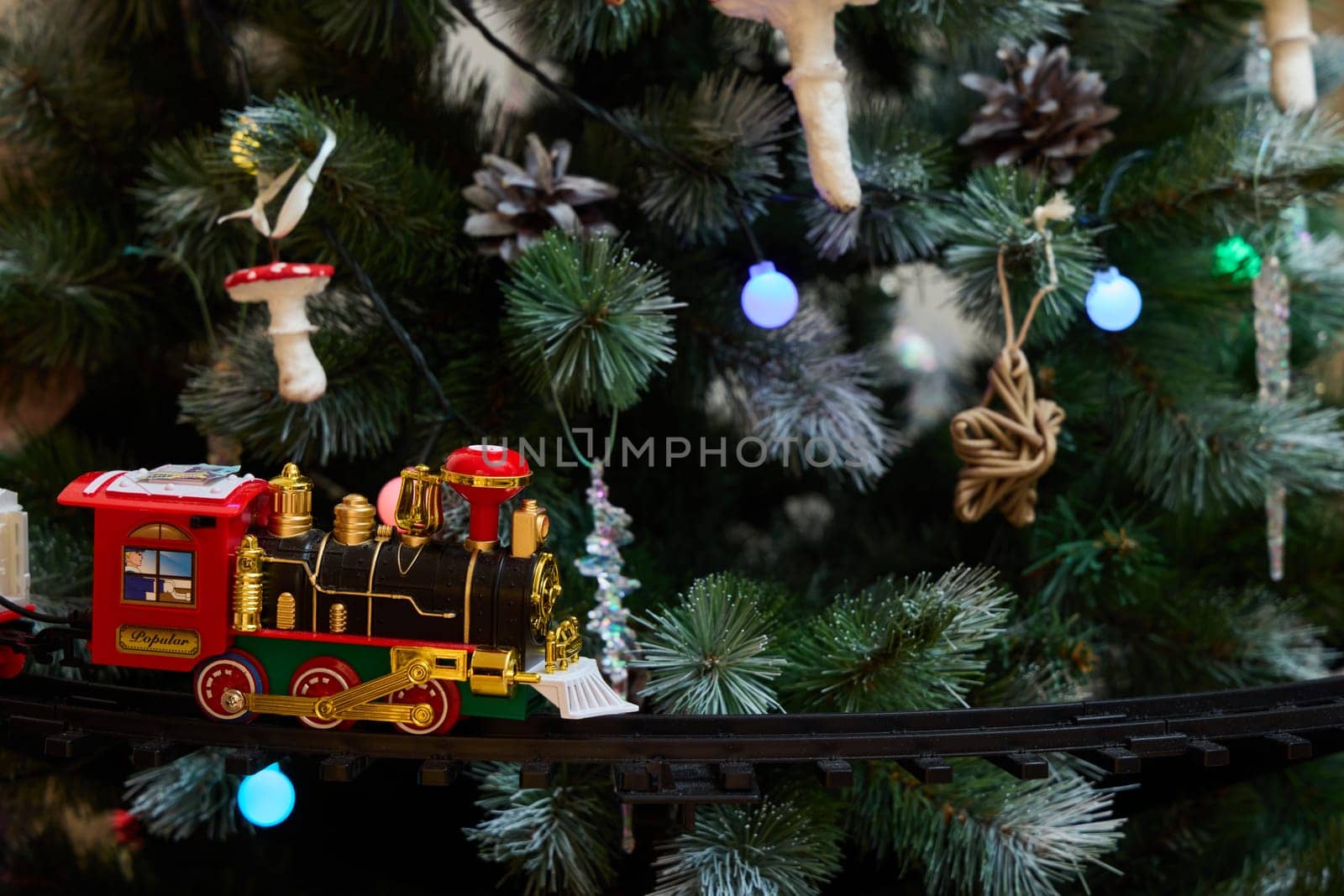 A charming toy train decorates a vibrant Christmas tree adorned with colorful ornaments and sparkling lights
