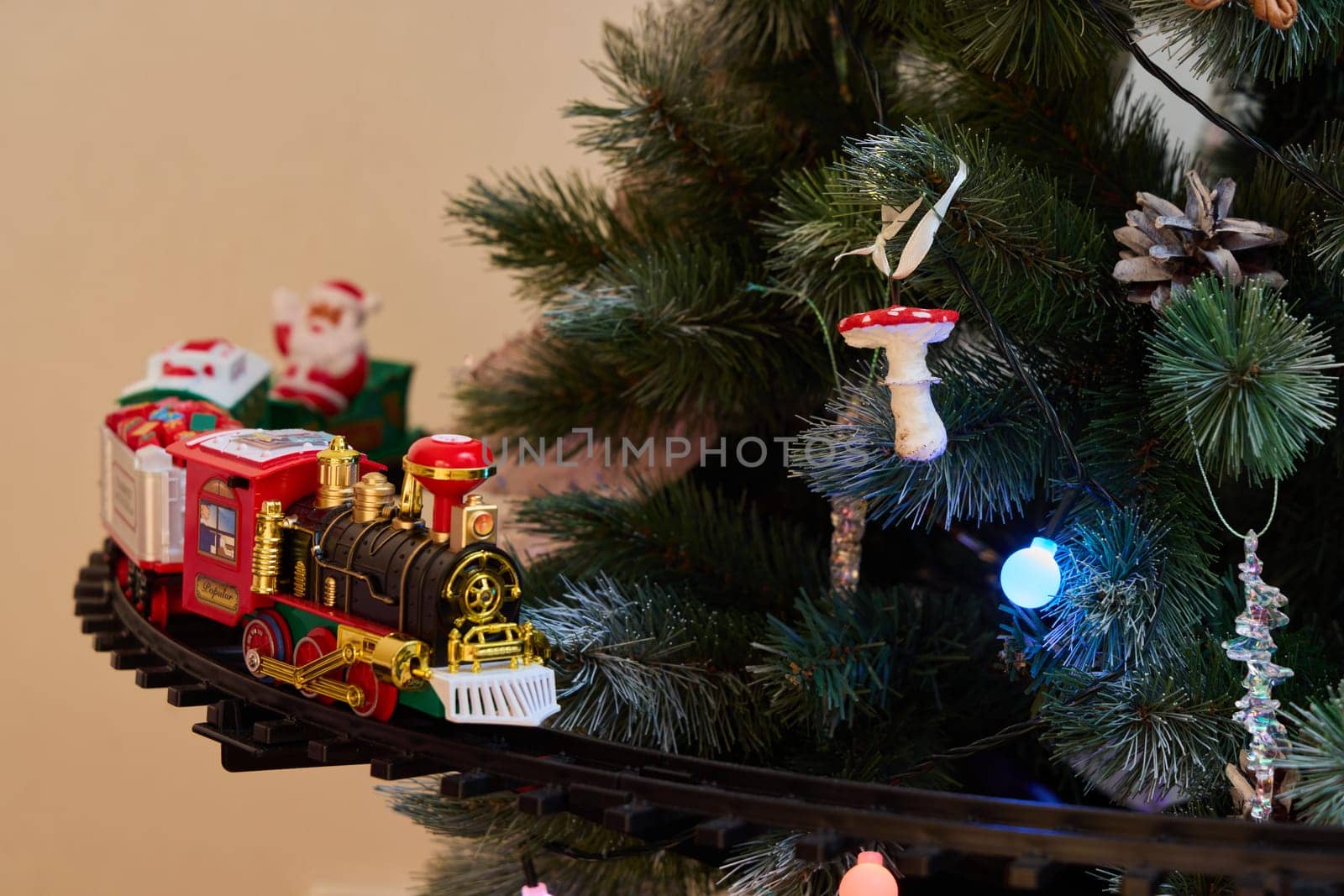 A charming train set gracefully circles a beautifully decorated Christmas tree adorned with festive lights