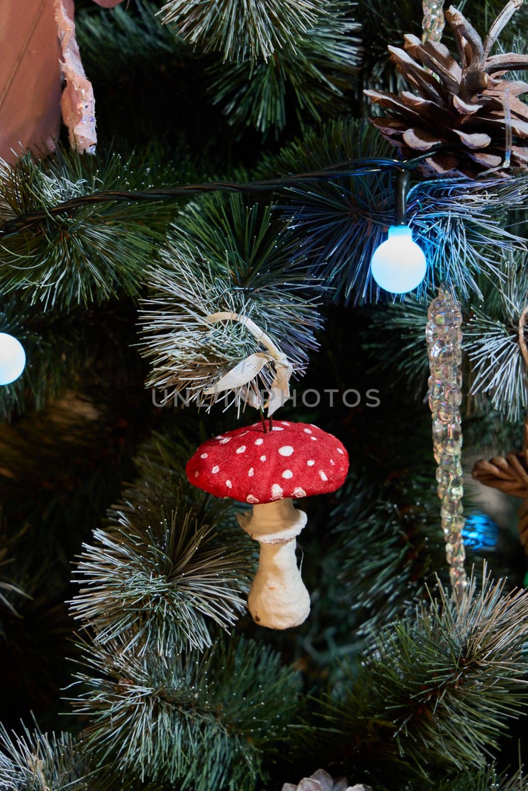 A red and white mushroom ornament hangs on a decorated Christmas tree, spreading festive holiday cheer