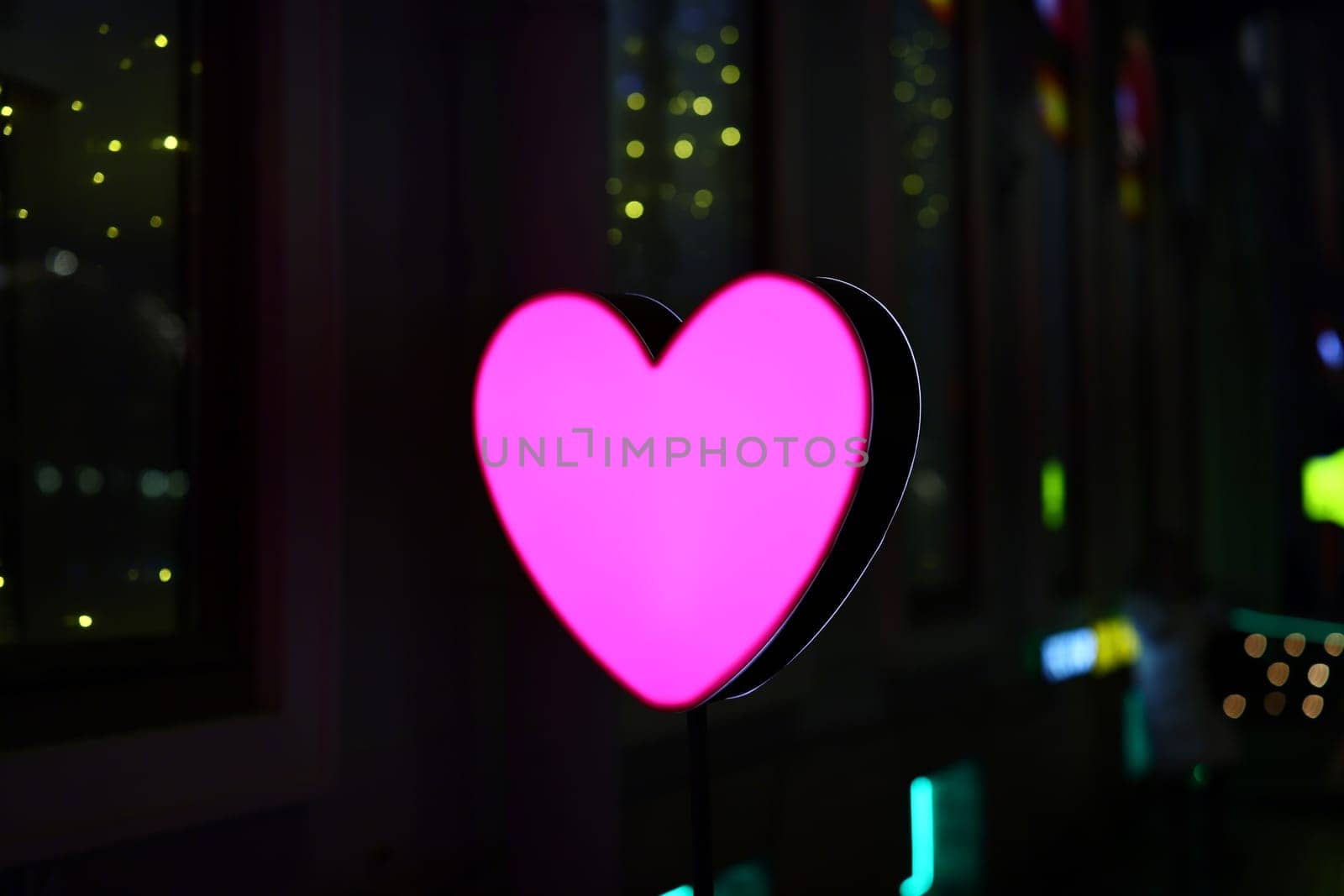 A beautifully glowing pink heartshaped sign brings a delightful romantic vibe to the cityscape at night