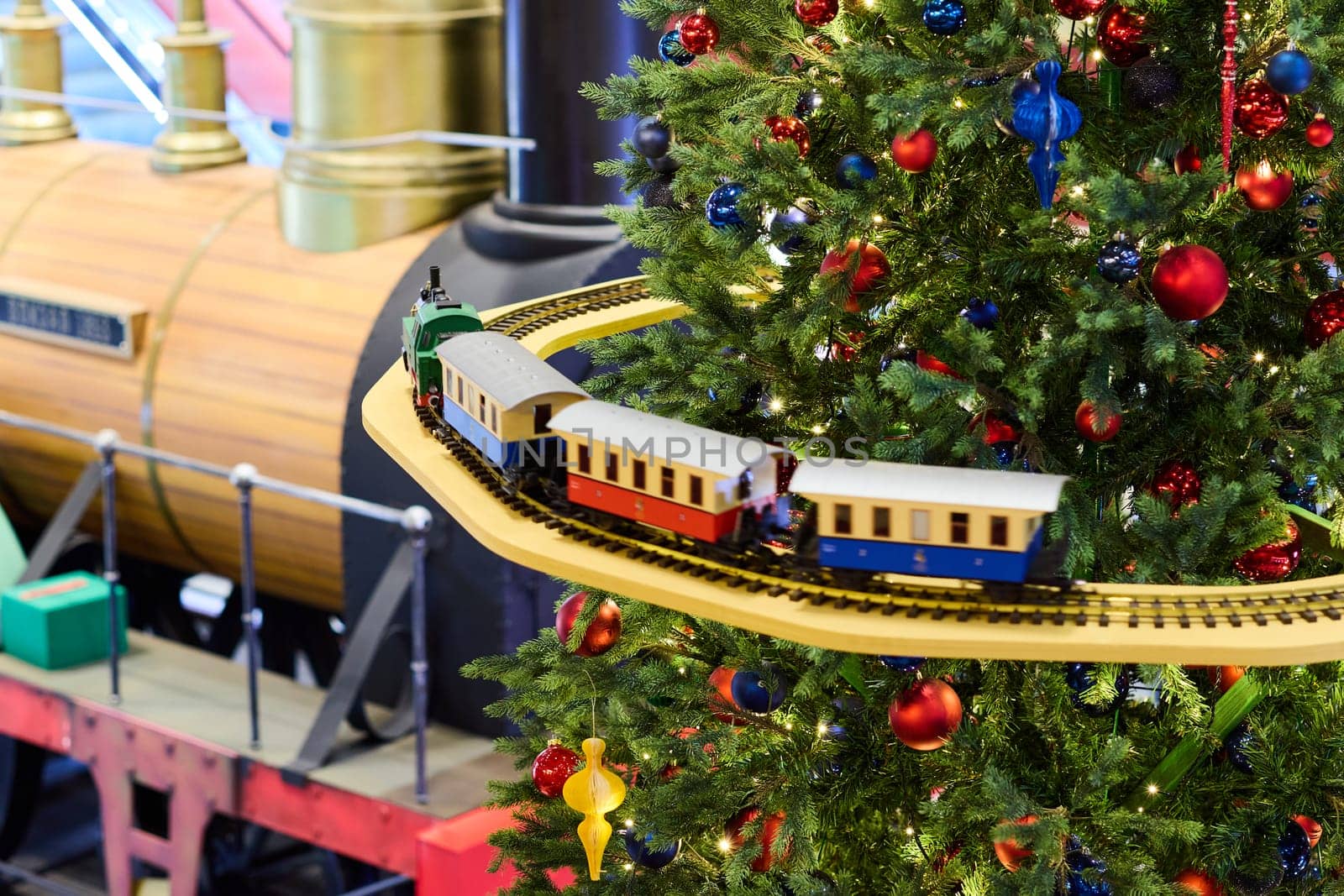 A colorful train gracefully circles around a beautifully decorated Christmas tree, bringing joy and cheer