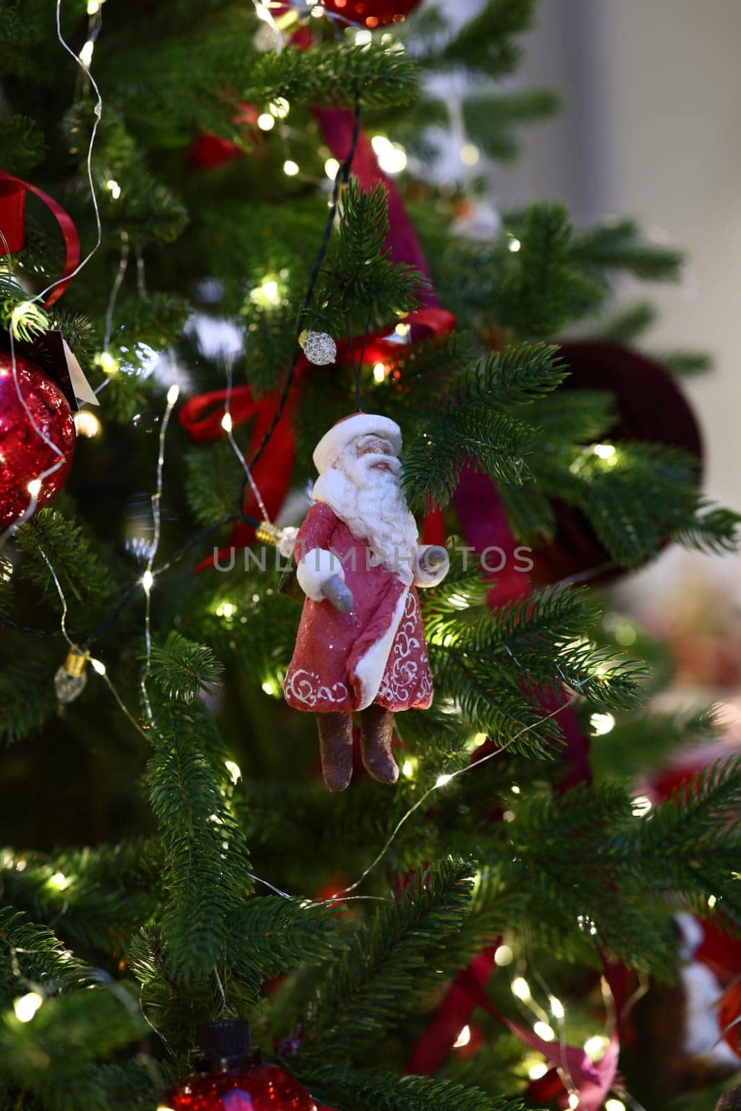 A charming Santa ornament gracefully hangs on a beautifully decorated Christmas tree filled with joy and warmth