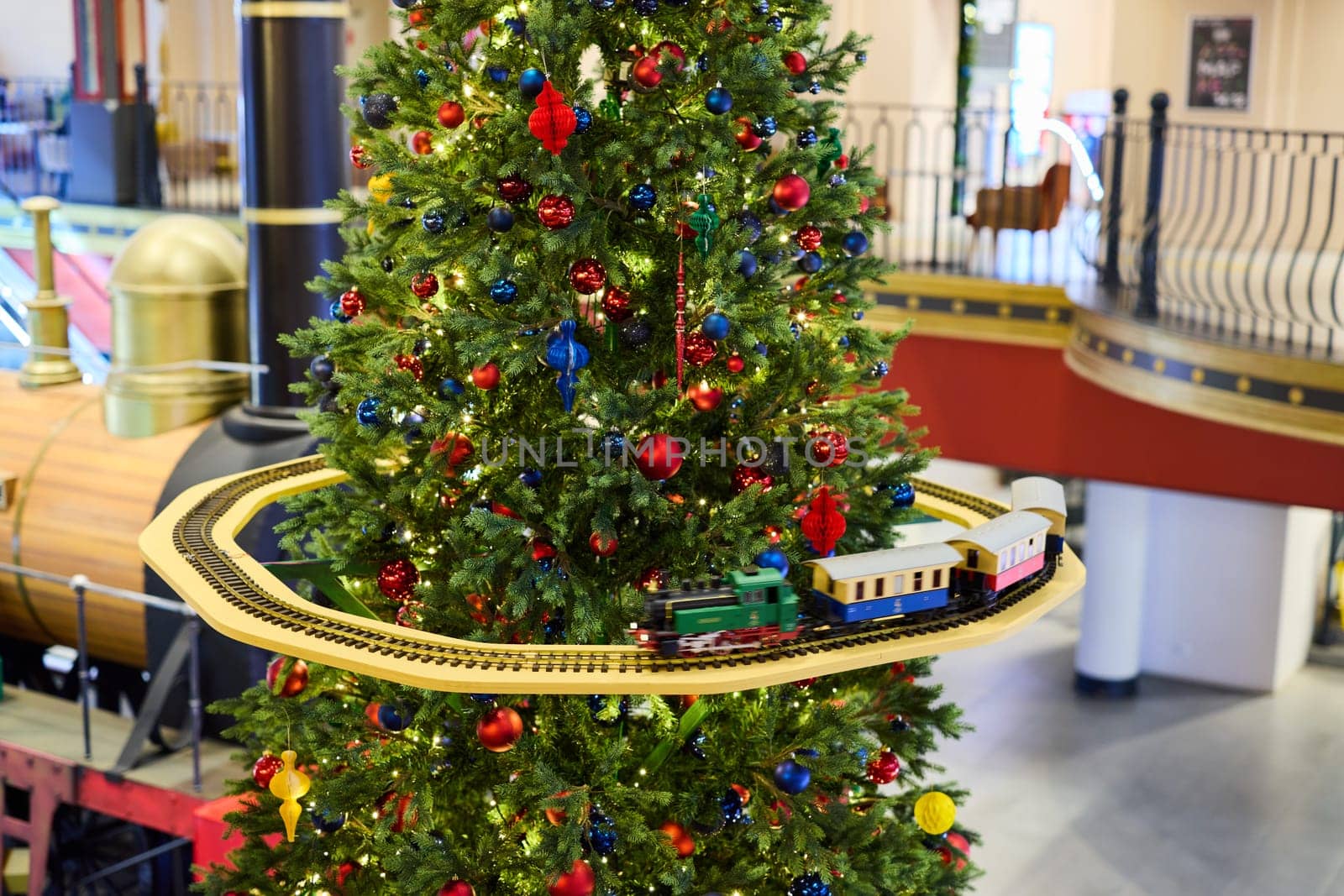 A vibrant Christmas tree with colorful ornaments and lights, featuring a train track circling around it