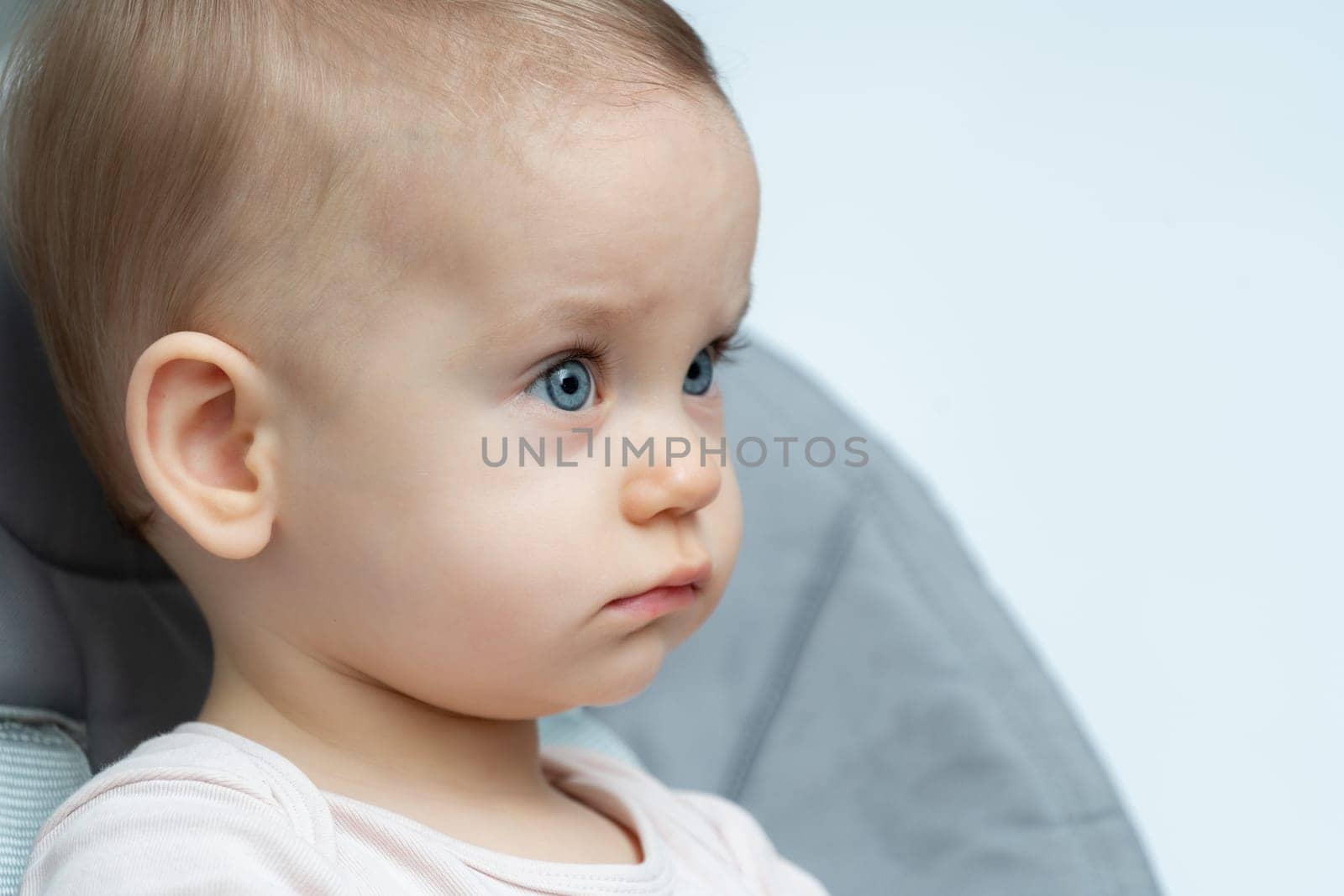 Thoughtful baby with bright blue eyes and a side profile