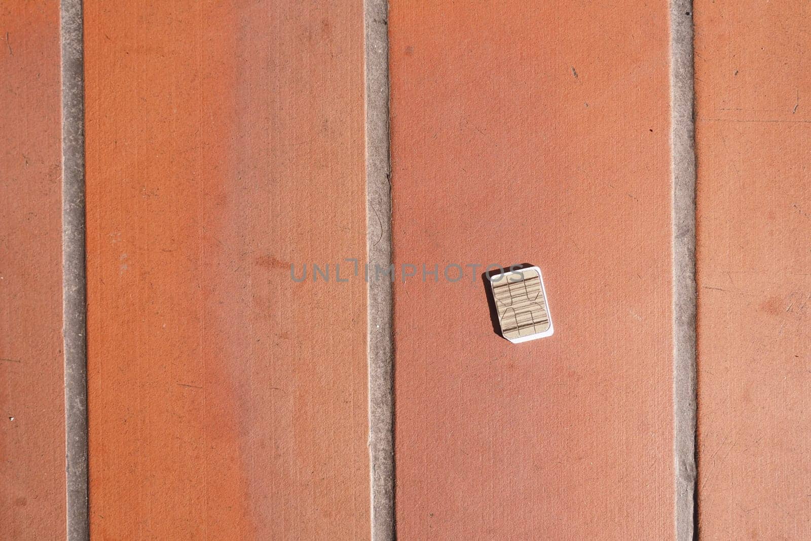 a phone sim card dropped on a tiles floor. lost sim card concept ,