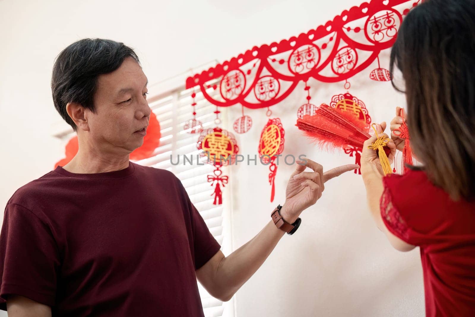 An elderly couple joyfully prepares their home for Chinese New Year showcasing the warmth of tradition and togetherness.