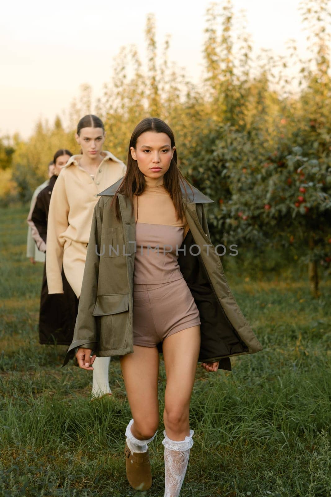 A group of stylish girls in stylish clothes at a fashion show in the garden.